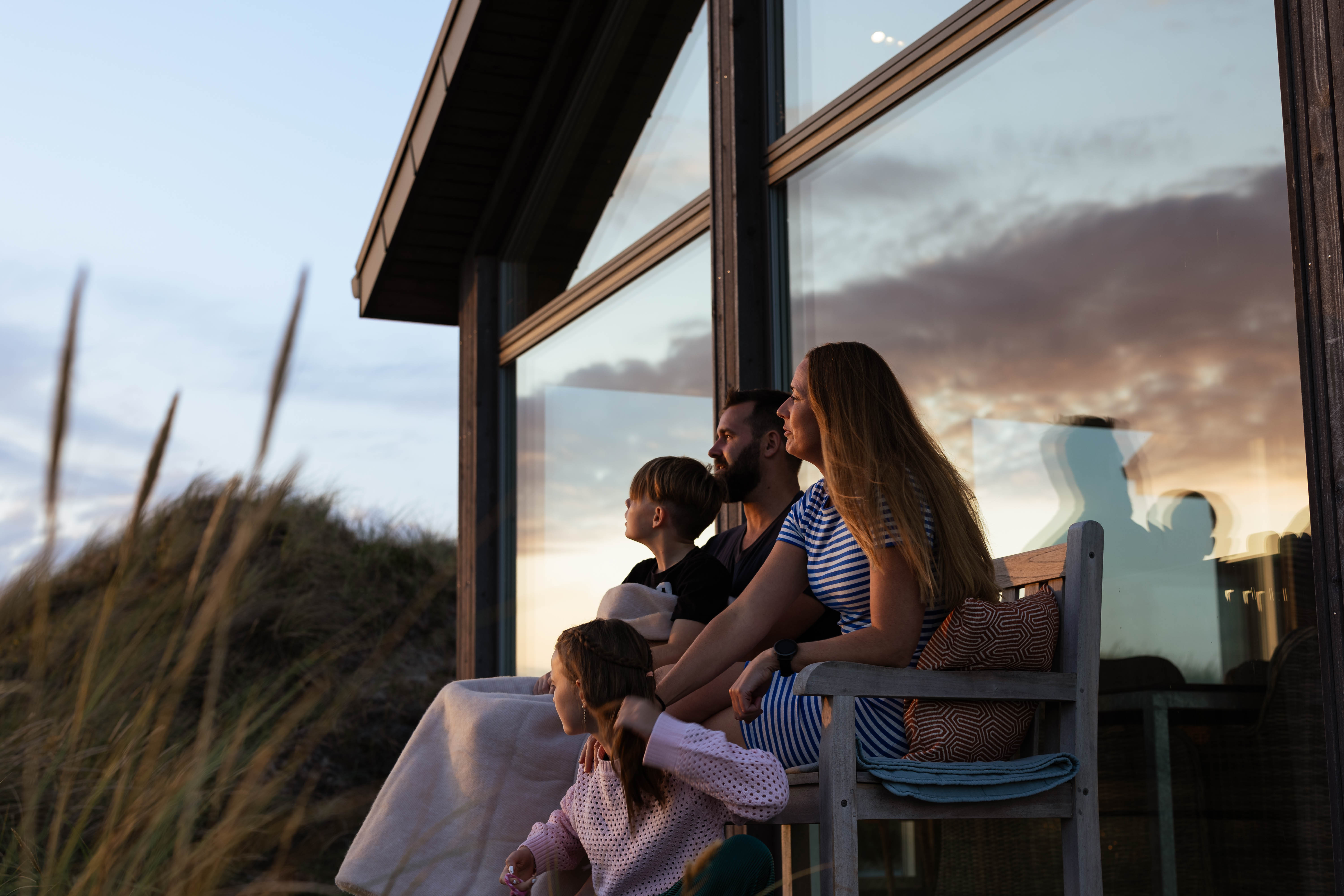 Familie sitzt vor einem Ferienhaus