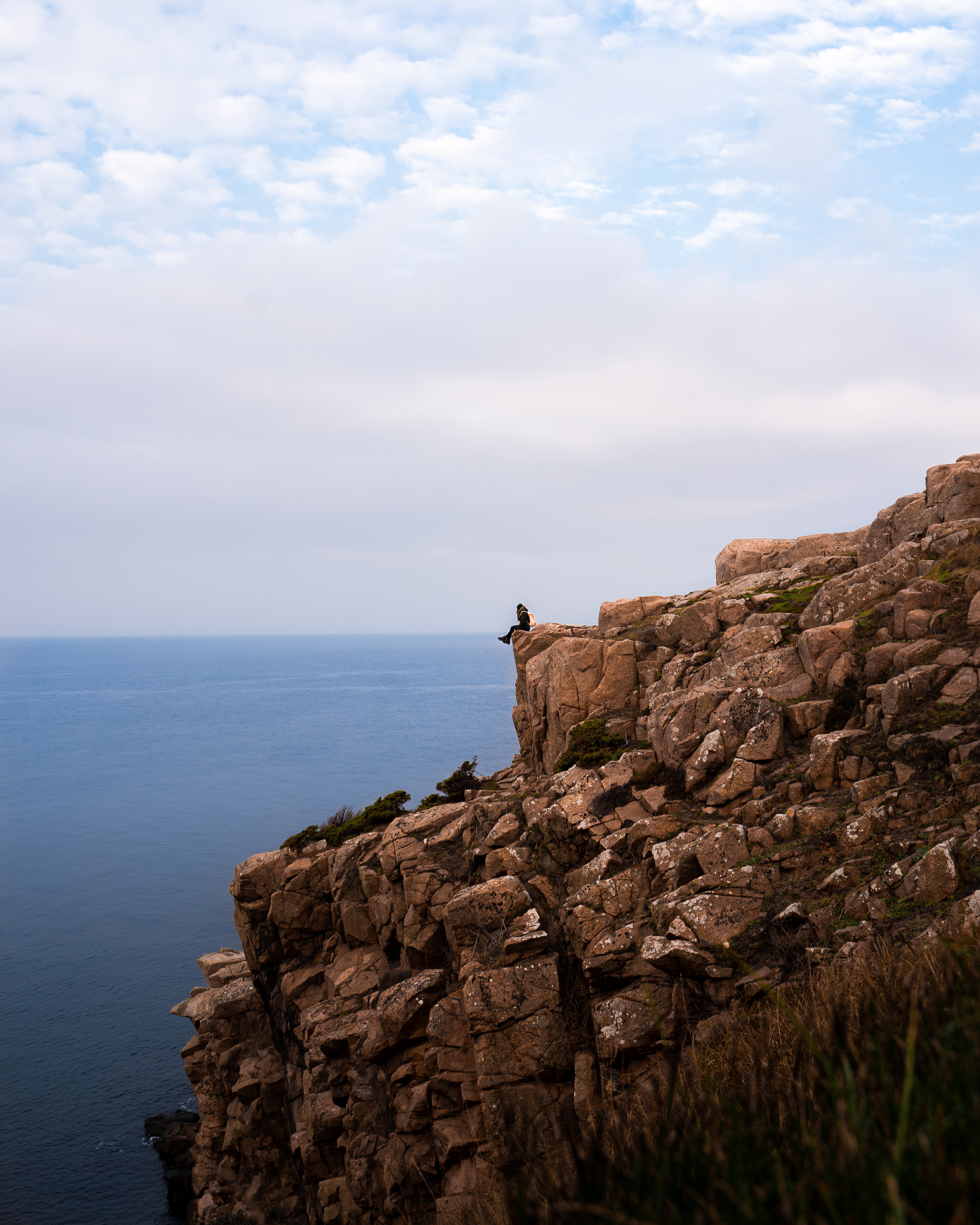Wanderer auf einer Klippe sitzend auf Bornholm