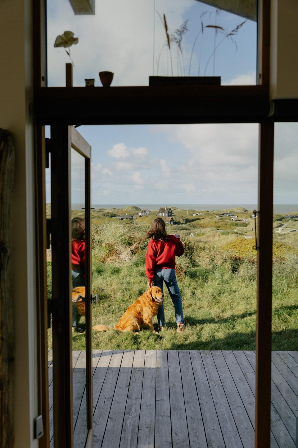 Woman and dog standing outside a holiday home in Denmark