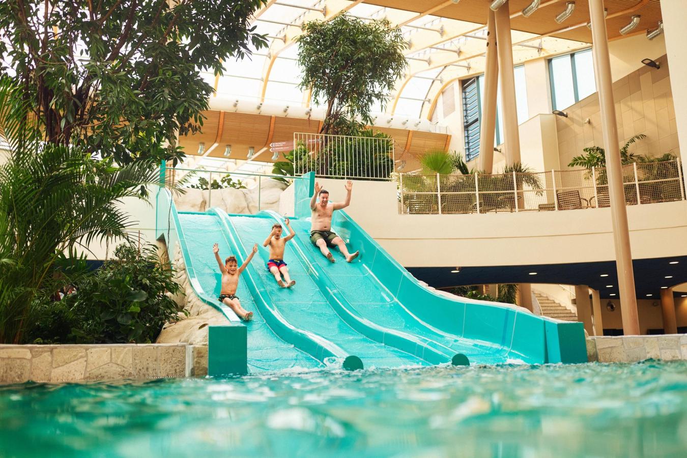 Familie gaat van de glijbaan in Aquadome, het zwemparadijs van Center Parcs Nordborg Resort