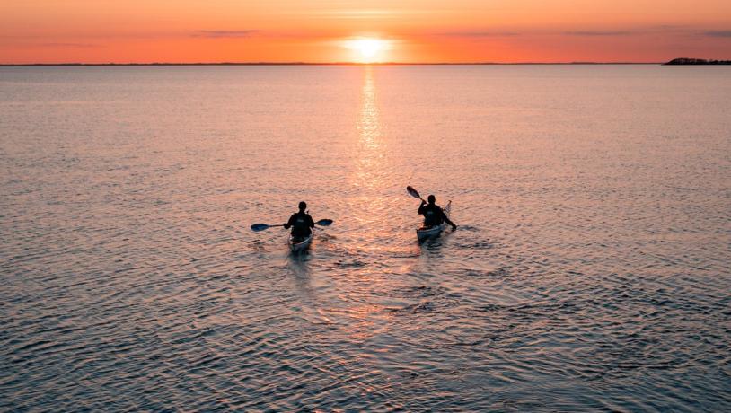 to personer kajakkpadler i solnedgangen ved Assens på Fyn, Danmark