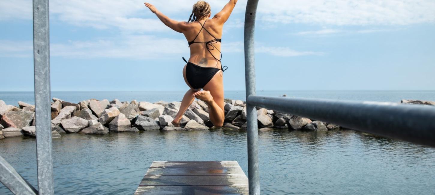 Person jumping in water at Svaneke harbour in Bornholm