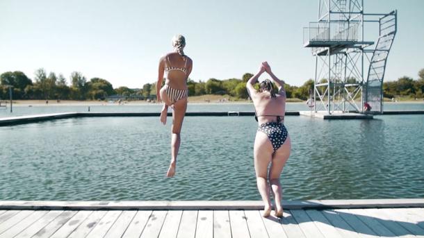 Two women jumping into the open air swimming pool at Vestre Fjordpark in Aalborg, Denmark