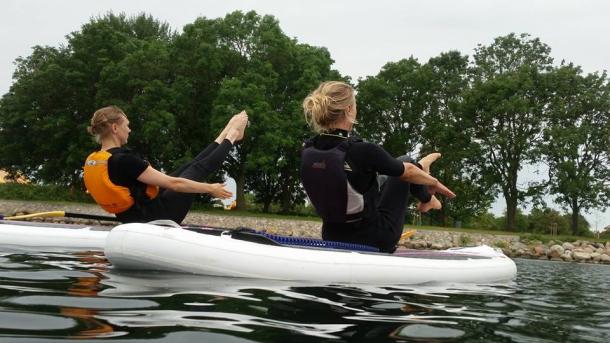 Two women do yoga balancing on a paddleboard in the Øresund Strait, near Copenhagen, Denmark