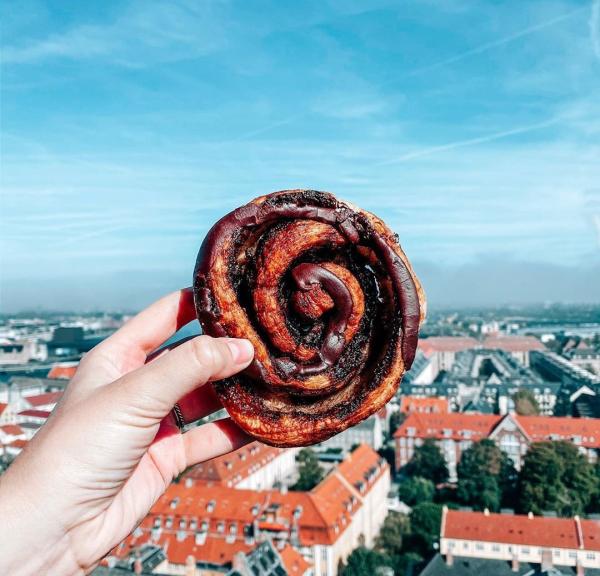 A danish pastry held out in front of the city streets