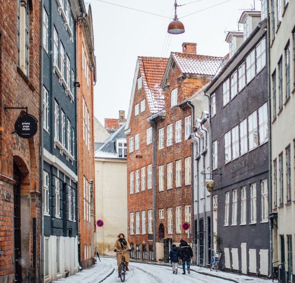 A woman cycles down snowy Magstræde in Copenhagen, Denmark