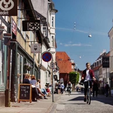 A cyclist driving past a cafe on Vestergade, Aarhus