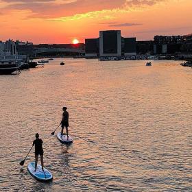 A couple paddleboard at sunset in the Teglholm district of Copenhagen