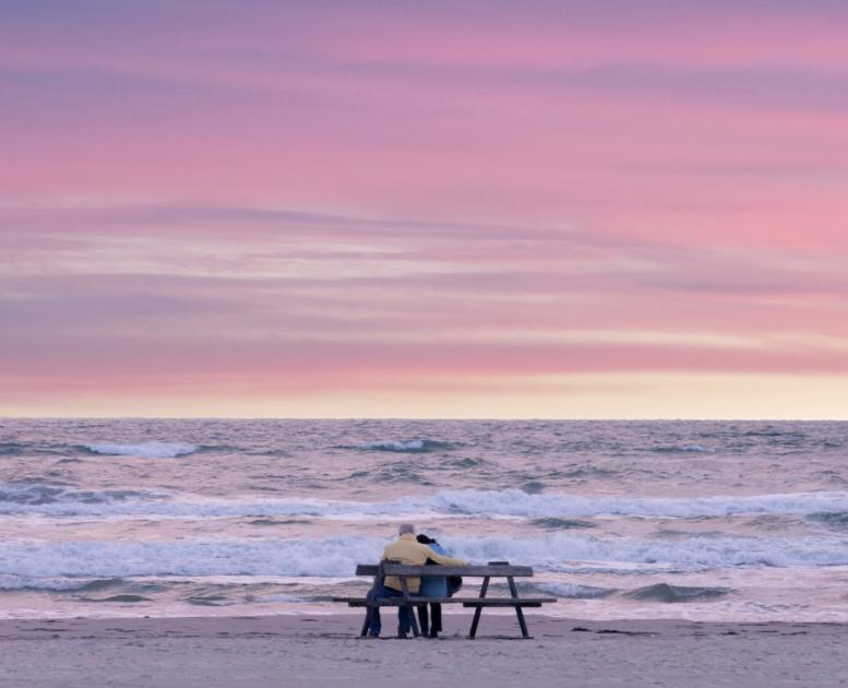 Couple sitting on a bench at Blokhus beach in North Jutland, Denmark